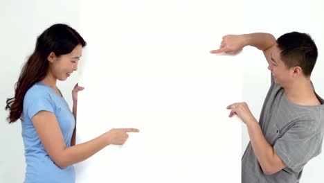 Pareja-Joven-Sonriente-Sosteniendo-Un-Cartel-En-Blanco