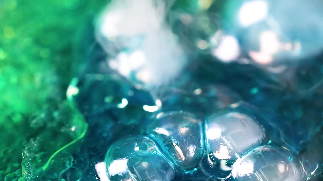 Close-up view of blue and green bubbles interacting in a mesmerizing fluid motion.