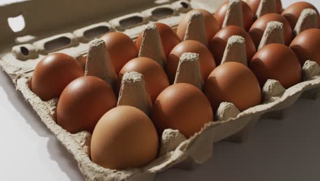 close up of multiple eggs in a cardboard box on white surface