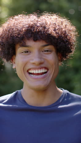 vertical video: smiling young man enjoying sunny day outdoors, feeling joyful and carefree