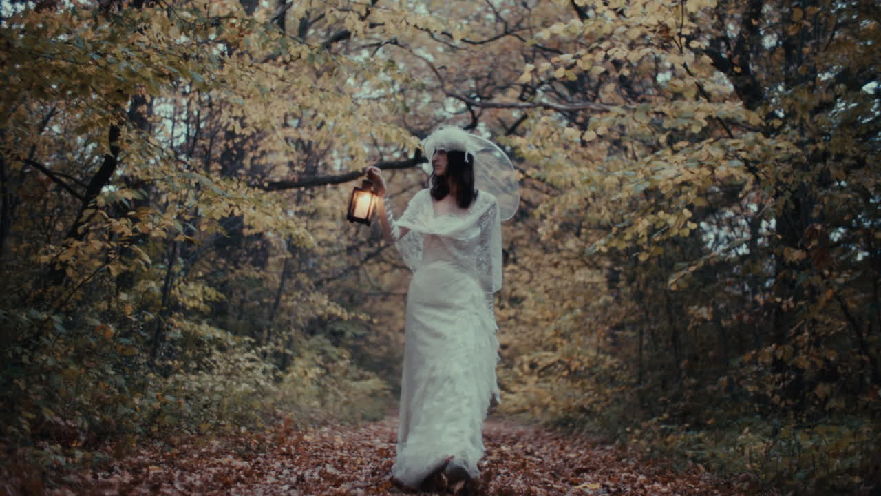A woman in a white dress holding a lantern in a mysterious autumn forest