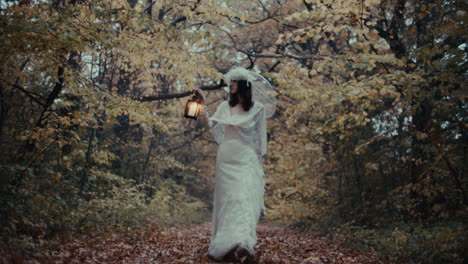 a woman in a white dress holding a lantern in a mysterious autumn forest