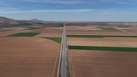 Aerial-view-of-divided-fields-on-a-cloudy-day-over-vast-farmland,-view-of-fields-under-cloudy-and-clear-sky