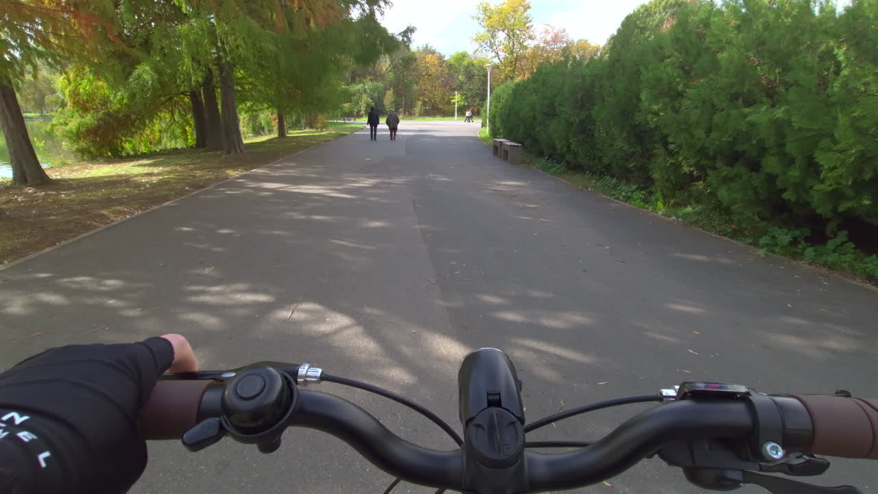 Cannes, France - November 5, 2025: First person view from a cyclist riding along a lakeside path lined with trees and bushes