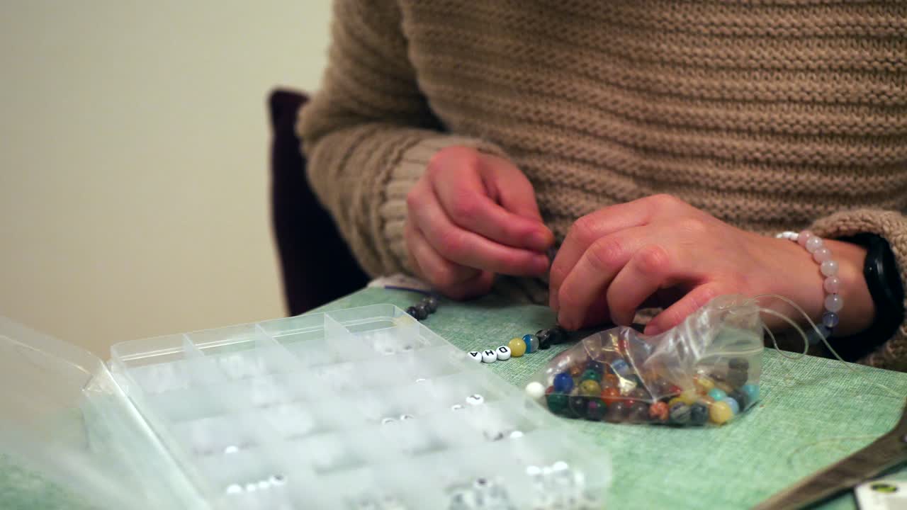 mujer haciendo una pulsera con nombre alimentando una cuerda a través de un agujero, cerrar