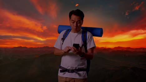 man hiking and surprised by a message on a phone at sunset