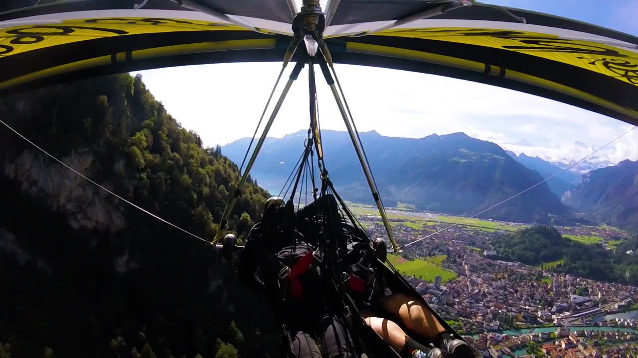 bonita toma aérea de gopro pov de un ala delta volando sobre los alpes y pueblos de suiza