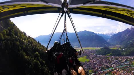 bonita toma aérea de gopro pov de un ala delta volando sobre los alpes y pueblos de suiza