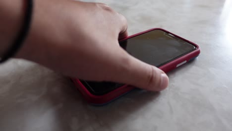 White-male-hand-picking-up-cell-phone-on-counter