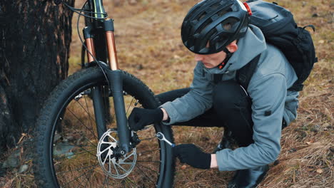 male cyclist repairing a mountain bike in the countryside