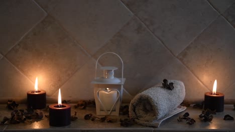 relaxing spa background with candles with flickering flame, some wooden petals and a towel