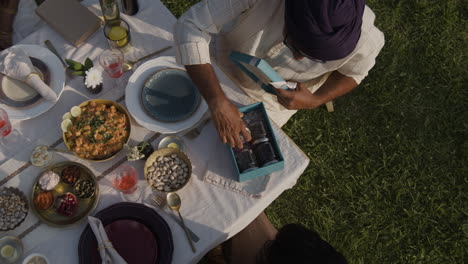 overhead view of people sharing a meal and exchanging gifts at an outdoor picnic
