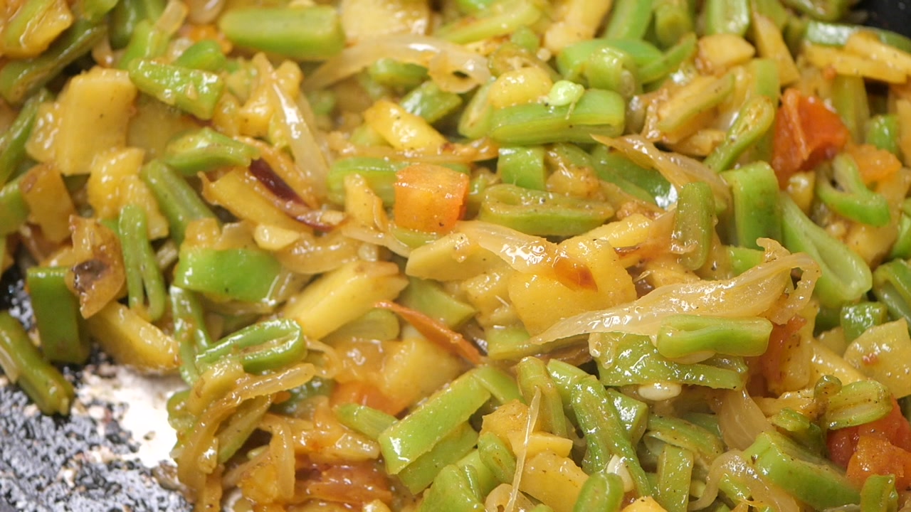 Stirring Fresh Green Beans and Potatoes with Onions and Tomatoes in a Pan