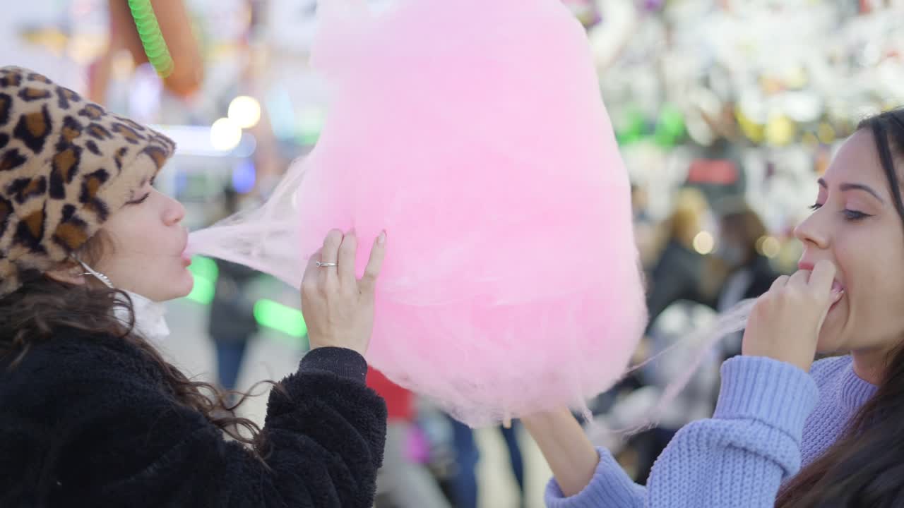 Women Enjoying Cotton Candy at a Festival