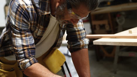 Side-view-of-carpenter-using-tablet-computer-while-working