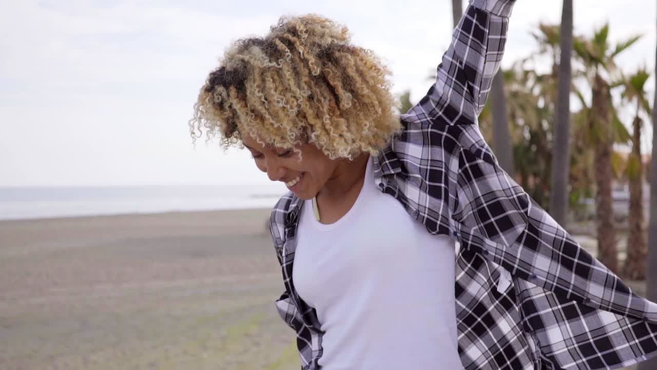 mladá žena kráčející na pláži se skateboardem