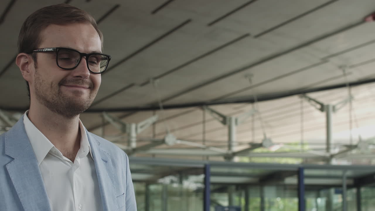 A young businessman an employee of a large company walks around a modern beautiful office and greets