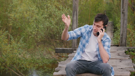 man on a wooden bridge talking on his phone