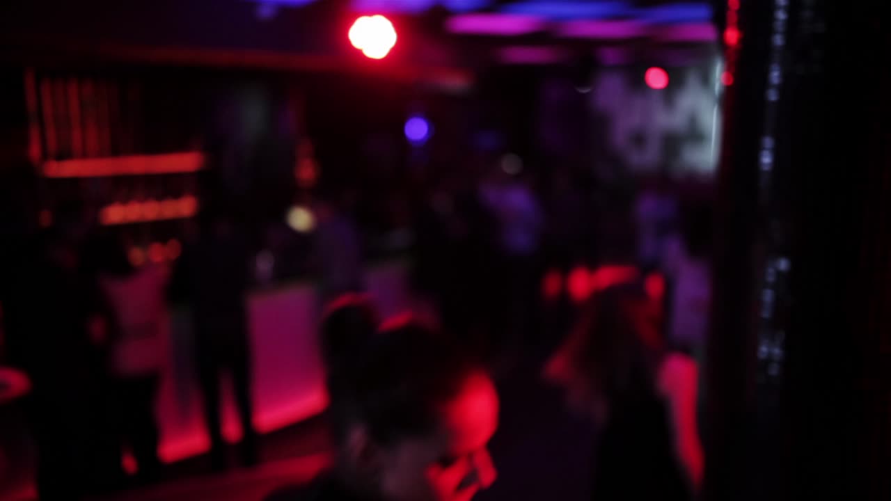Girl dancing at the nightclub near the column in the neon lights