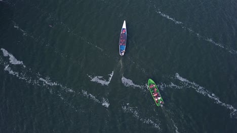 drone view from above of a blue boat and a green boat sailing together on a river