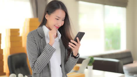 successful young asian businesswoman in office swiping for great news on mobile phone