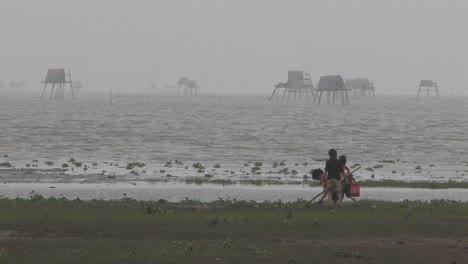 two children and one adult digging in sand at a foggy beach in vietnam