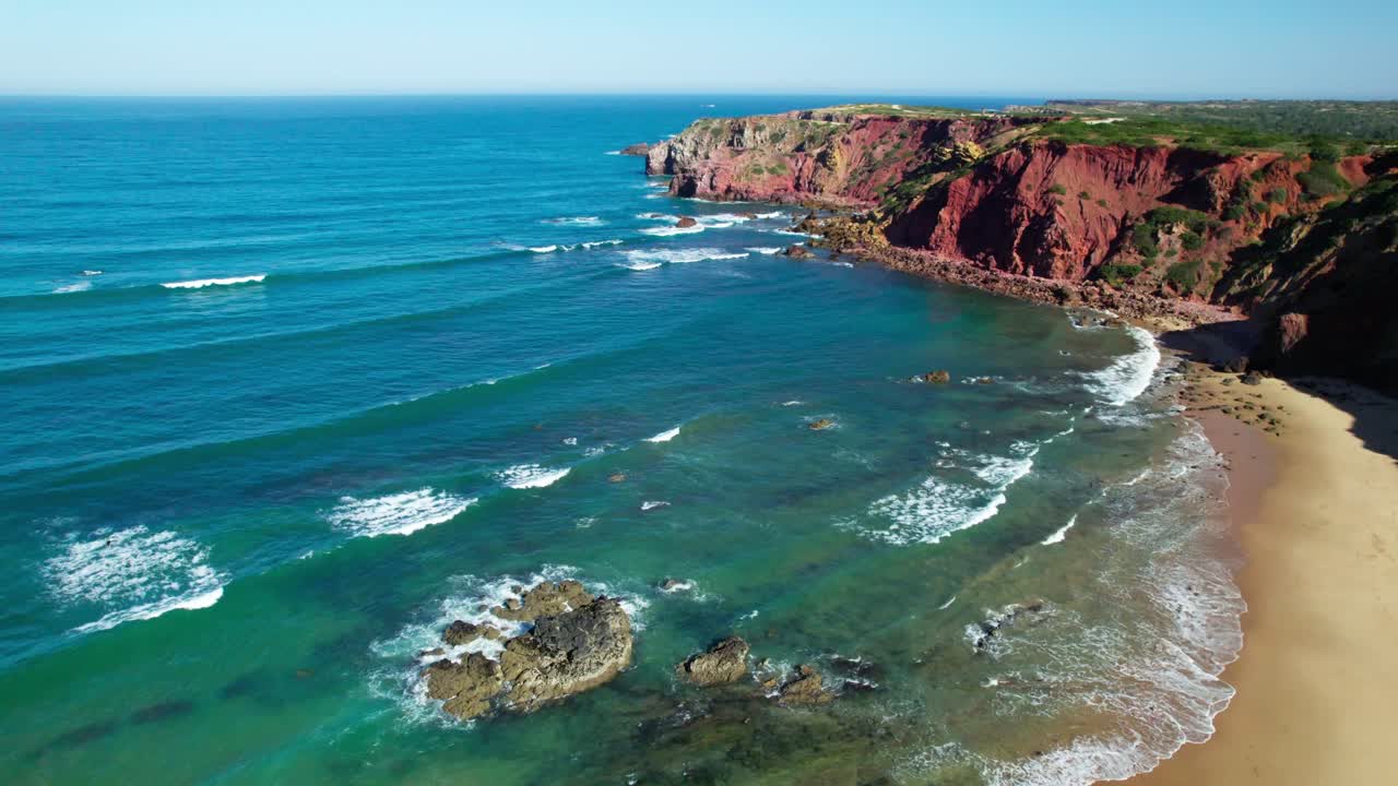 Scogliere rosse di un promontorio vicino al mare blu in estate. Ripresa aerea.