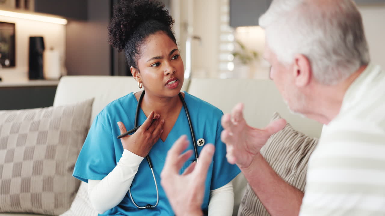 Nurse Discussing Health with Elderly Male Patient During Home Visit