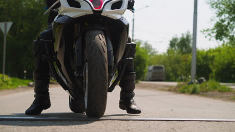 Skilled-biker-stops-motorcycle-by-metal-board-bar-on-road