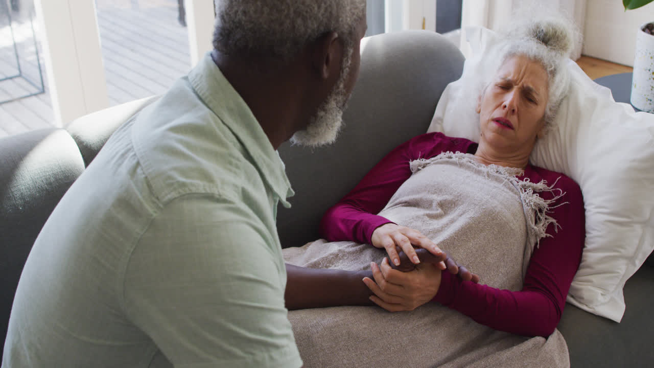 African american man taking care of his sick wife in the living room at home