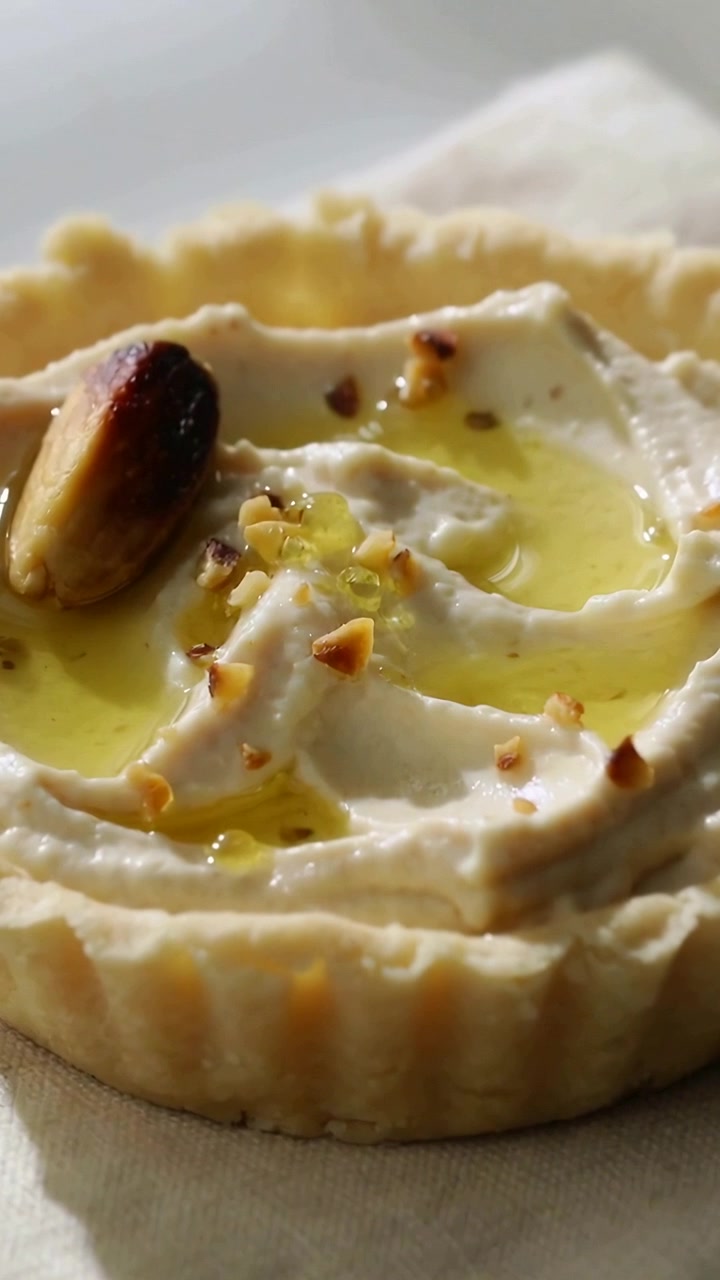Vertical video: Clip start moving camera back on napkin, showing tartlet cream pistachio texture
