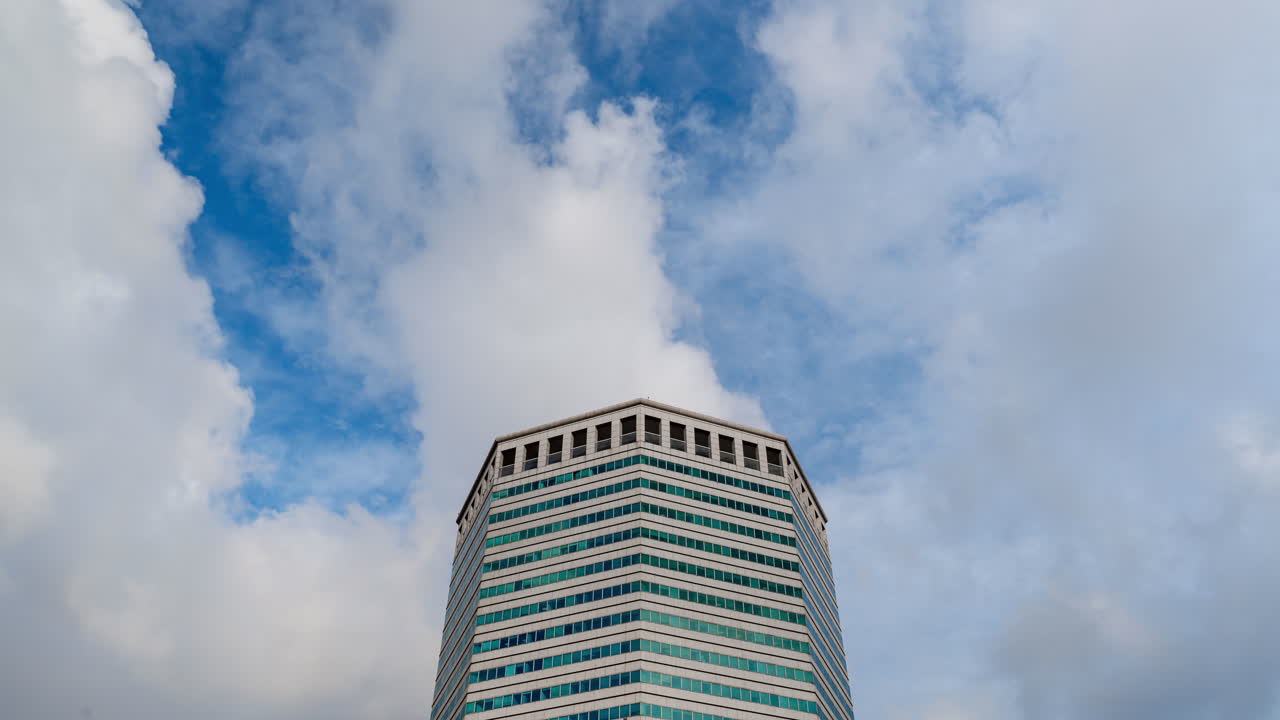 Timelapse of clouds drifting past a tall modern building