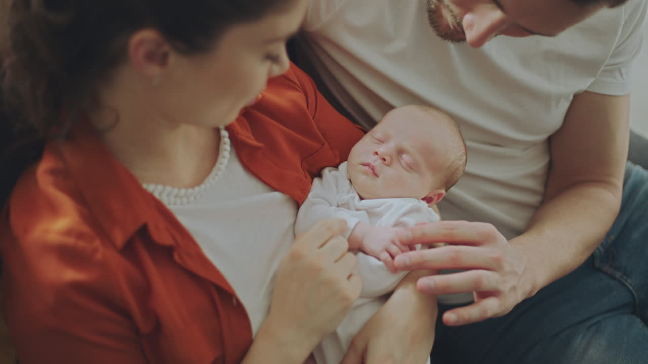 Parents lovingly holding a sleeping newborn baby