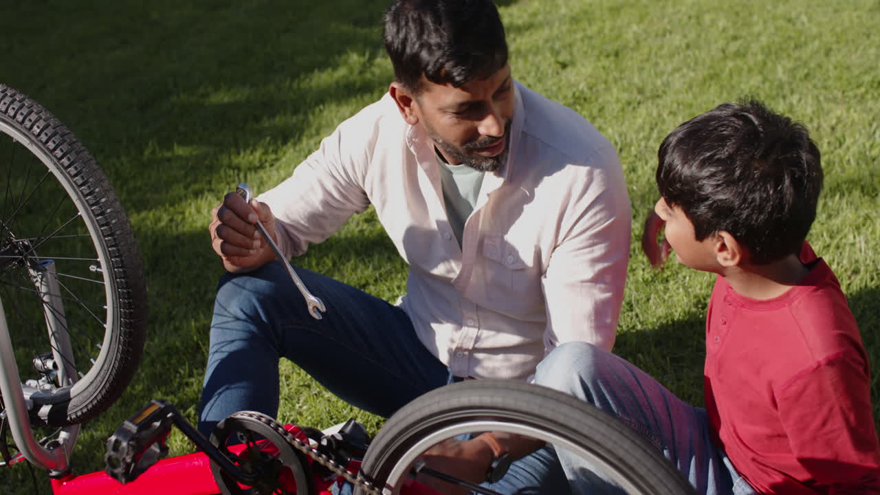 Fixing bicycle, Indian father and son bonding together outdoors on sunny day