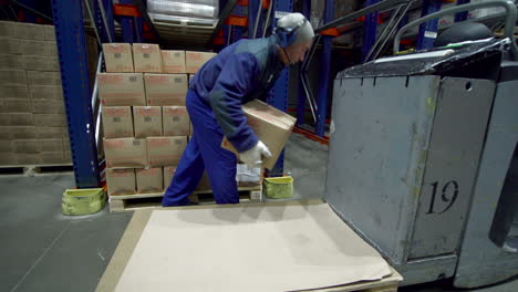 warehouse worker loading boxes onto pallet with forklift