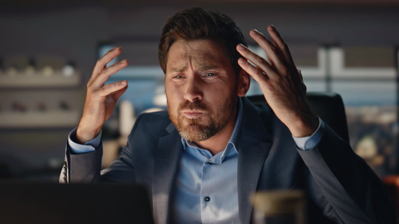 hombre loco de primer plano gesticulando con las manos en la oficina de city view por la noche. fracaso comercial