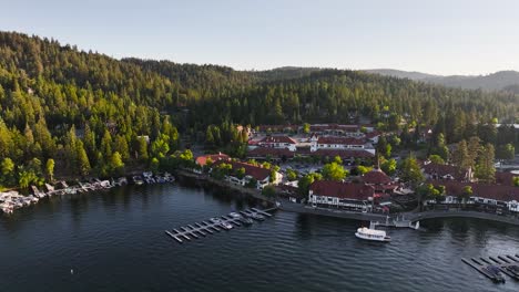 lake arrowhead village at sunset with sun rays beaming onto the trees in the hill tops over the marina with boats in view aerial trucking pan