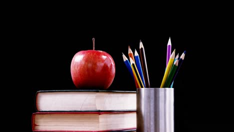 apple on book stack with color pencil on table