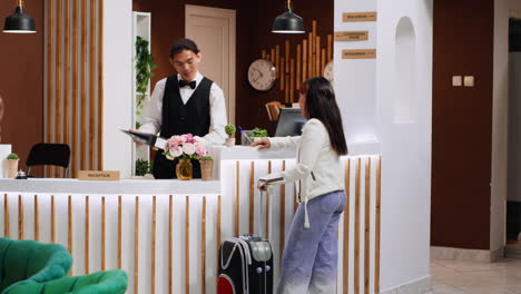 un huésped asiático de un hotel le pregunta a la recepcionista sobre las comodidades.