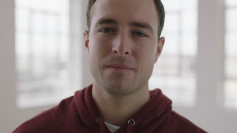 slow motion portrait of attractive young caucasian man looking focused serious at camera intense male staring in modern apartment room