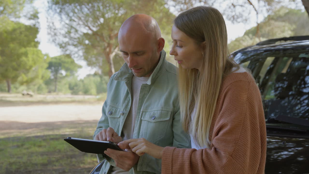 pareja joven usando una tableta digital cerca del coche