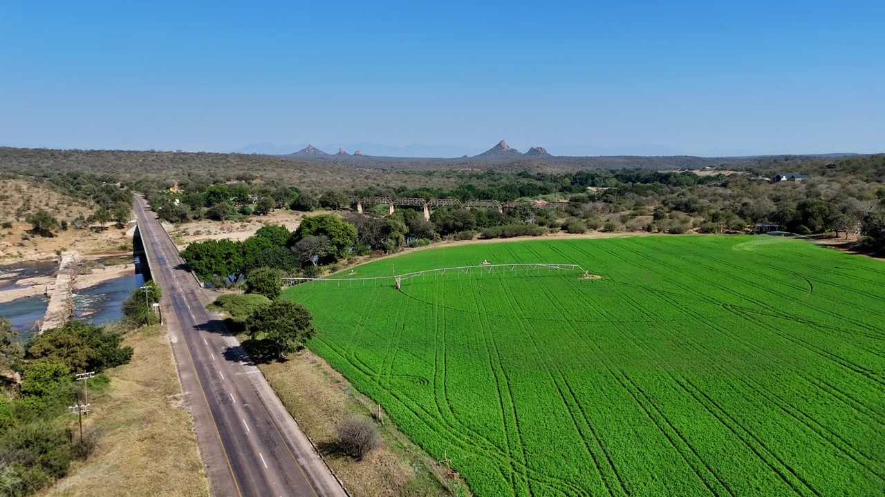 Ascenso aéreo que revela tierras de cultivo verdes junto al cruce del río Olifants.