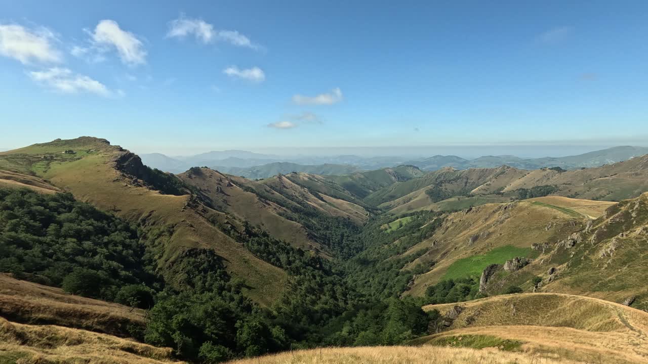 Rugged green mountain range landscape extends to distant sunny horizon