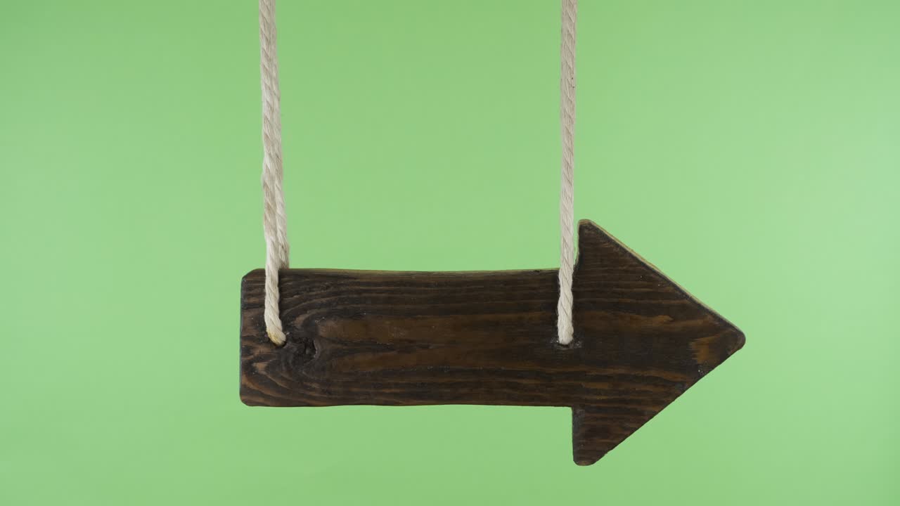 Wooden pointer sways in the wind. Isolated on a green screen.