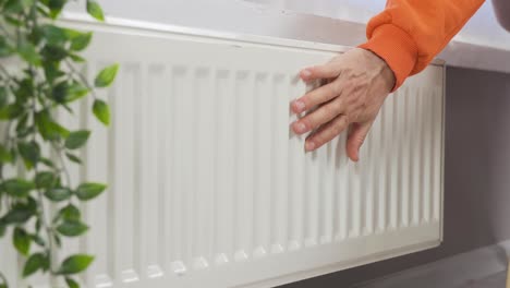 mano de persona ajustando la temperatura en el termostato para controlar el calor en el sistema de calefacción central de la casa.