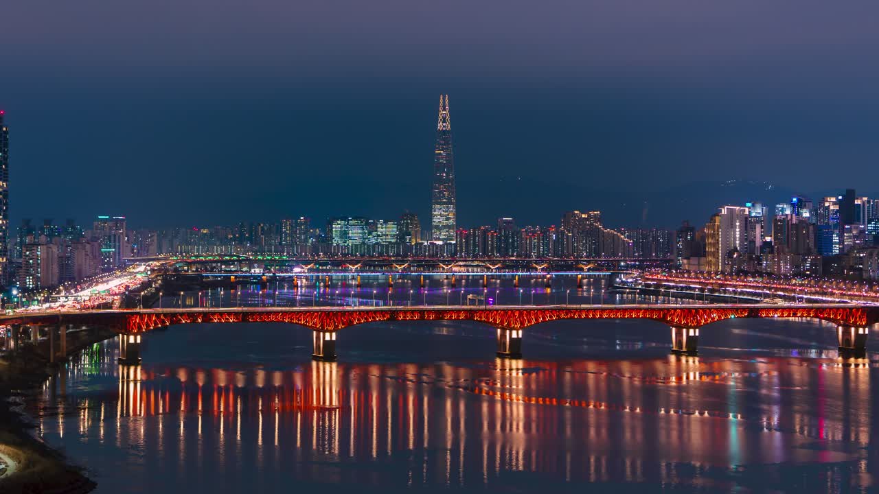 Straordinario hyperlapse aereo notturno che si muove lungo il ponte Seongsu sul fiume Han con la torre Lotte illuminata.