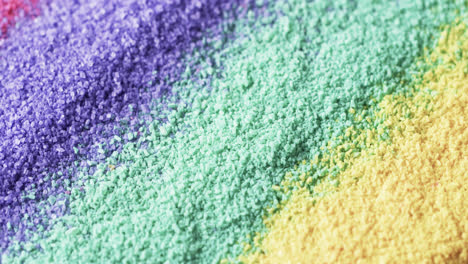 Video-of-close-up-of-rainbow-coloured-sand-grains-and-copy-space-background