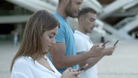 Thoughtful-people-standing-in-row-and-using-digital-devices