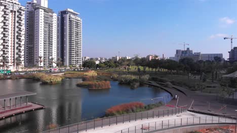 modern urban park with pond, walkway, and high-rise buildings