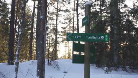 Cartel-En-Un-Bosque-Cubierto-De-Nieve-Con-Una-Flecha-Verde-Que-Apunta-A-Turisthytta-En-Noruega